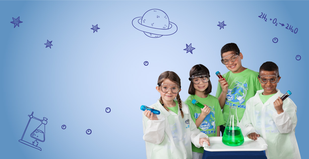 2 kids in lab coats, 2 in green t shirts holding test tubes with different color liquid inside. A beaker with a green liquid.