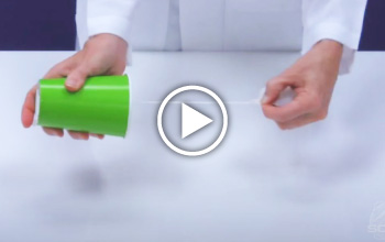 A mad science instructor holding a green cup and pulling a string from the cup with the other hand.